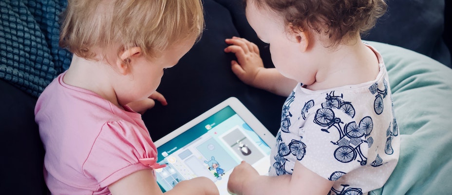 Two young children looking at an iPad together